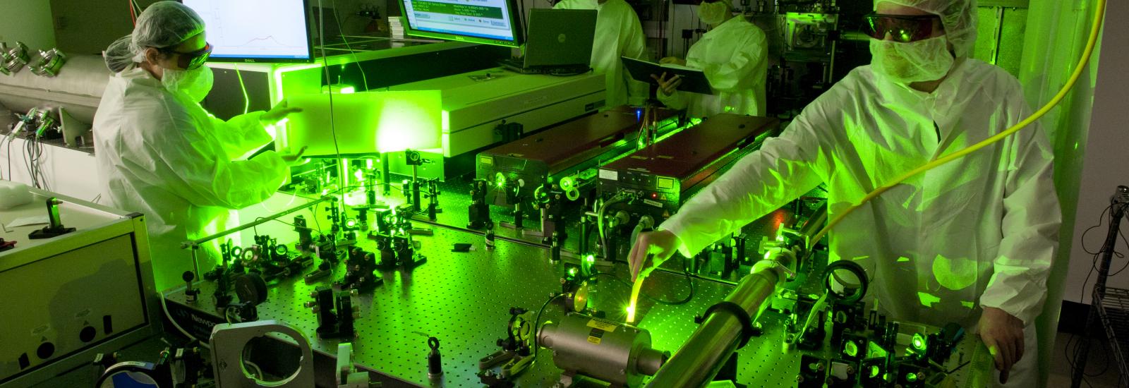 Physicists working in laser lab illuminated by green laser scatter